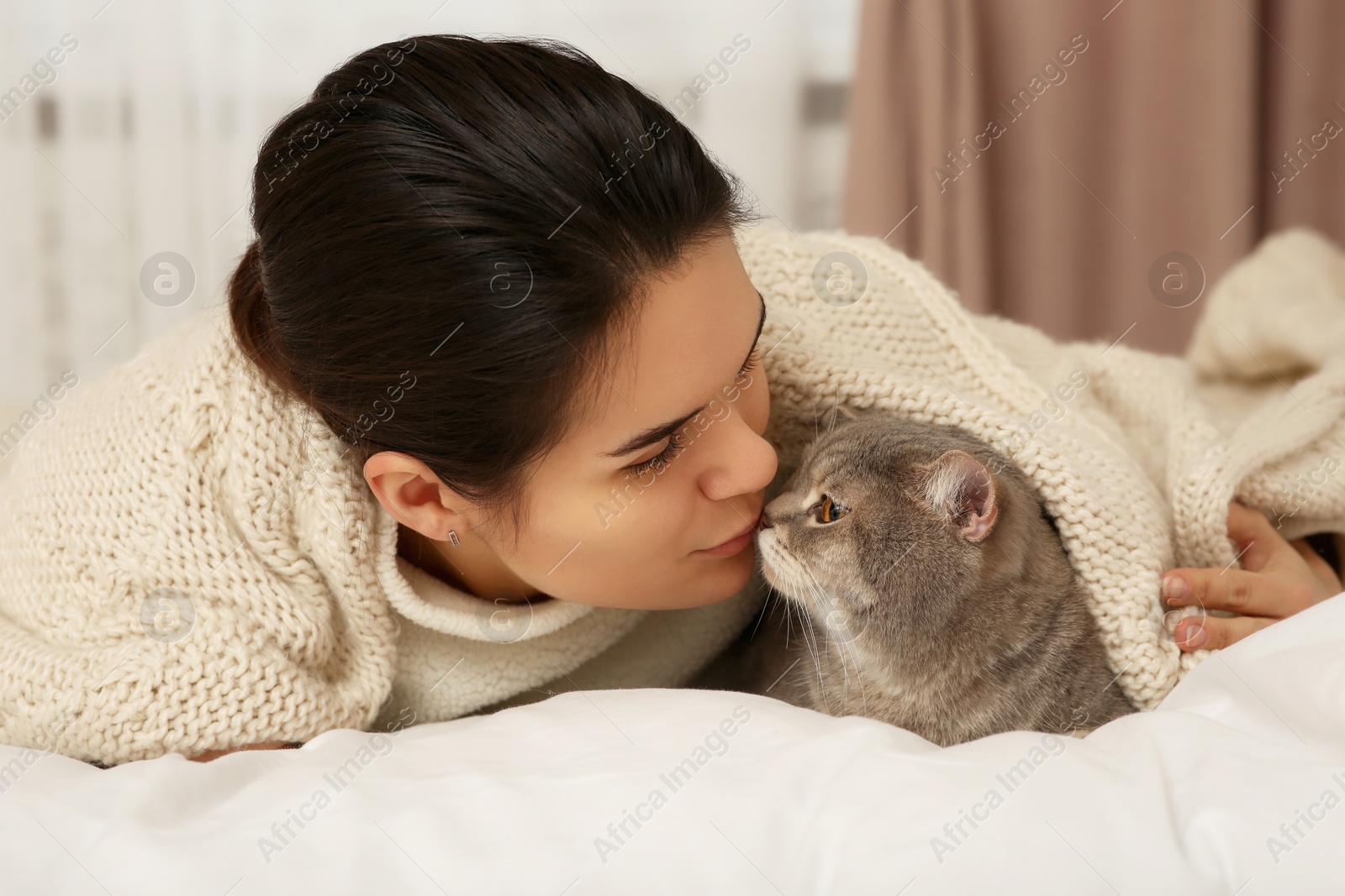 Photo of Young woman kissing her adorable cat at home