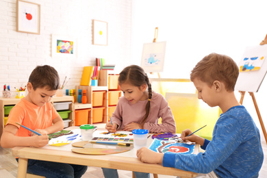 Photo of Cute little children painting at table in room