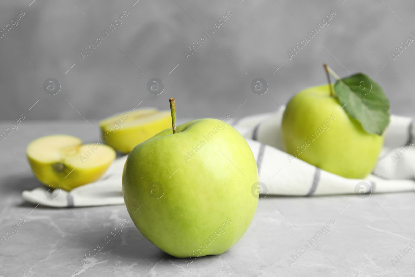 Photo of Fresh ripe green apples on grey stone table against blue background, space for text