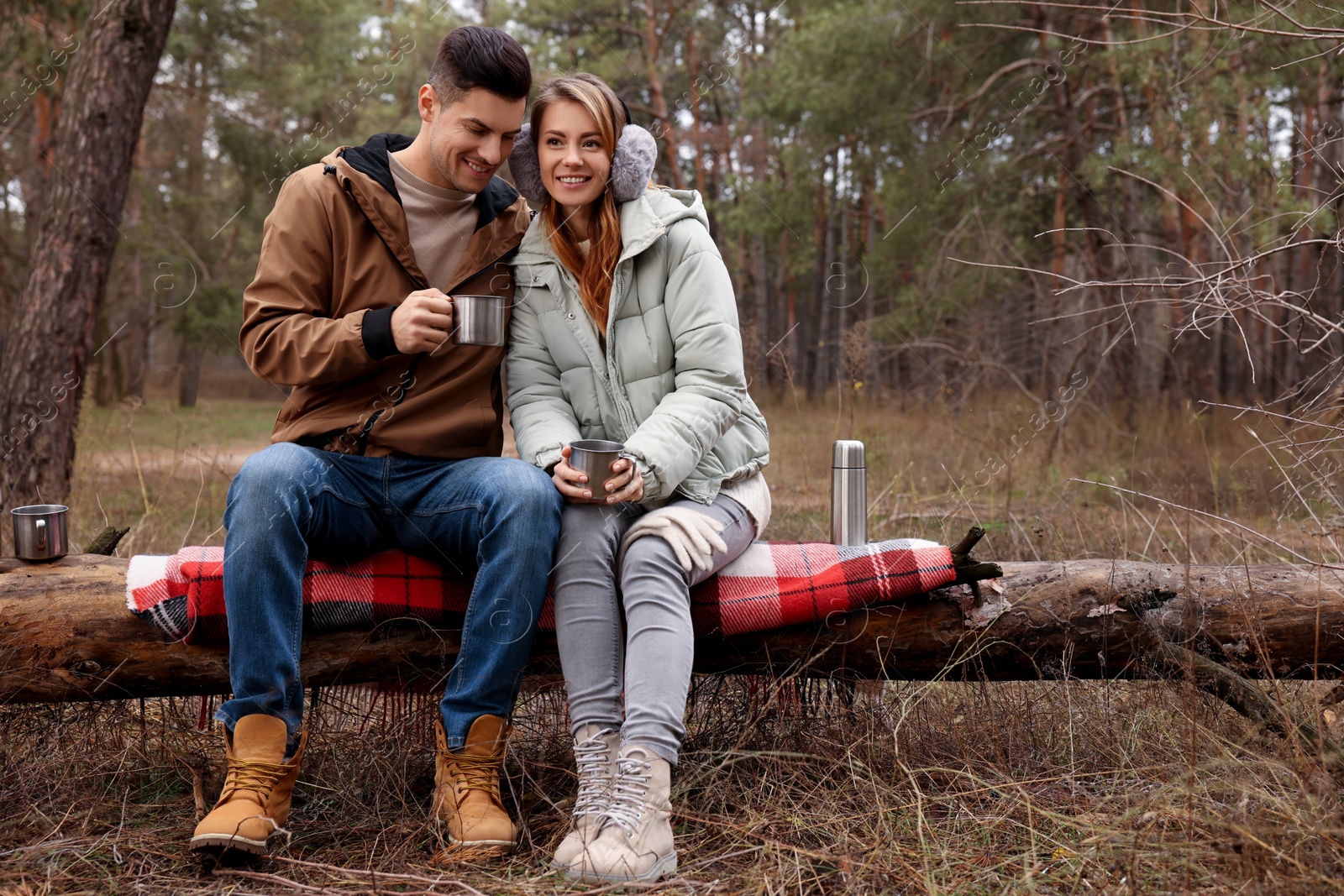 Photo of Happy couple with hot drinks spending time together in forest