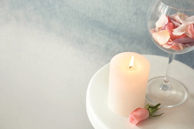 Photo of Candle with floral decor on table against color background