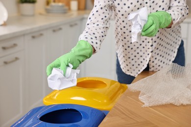 Photo of Garbage sorting. Woman throwing crumpled paper into trash bin in room, closeup