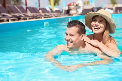 Photo of Happy couple relaxing in blue swimming pool outdoors