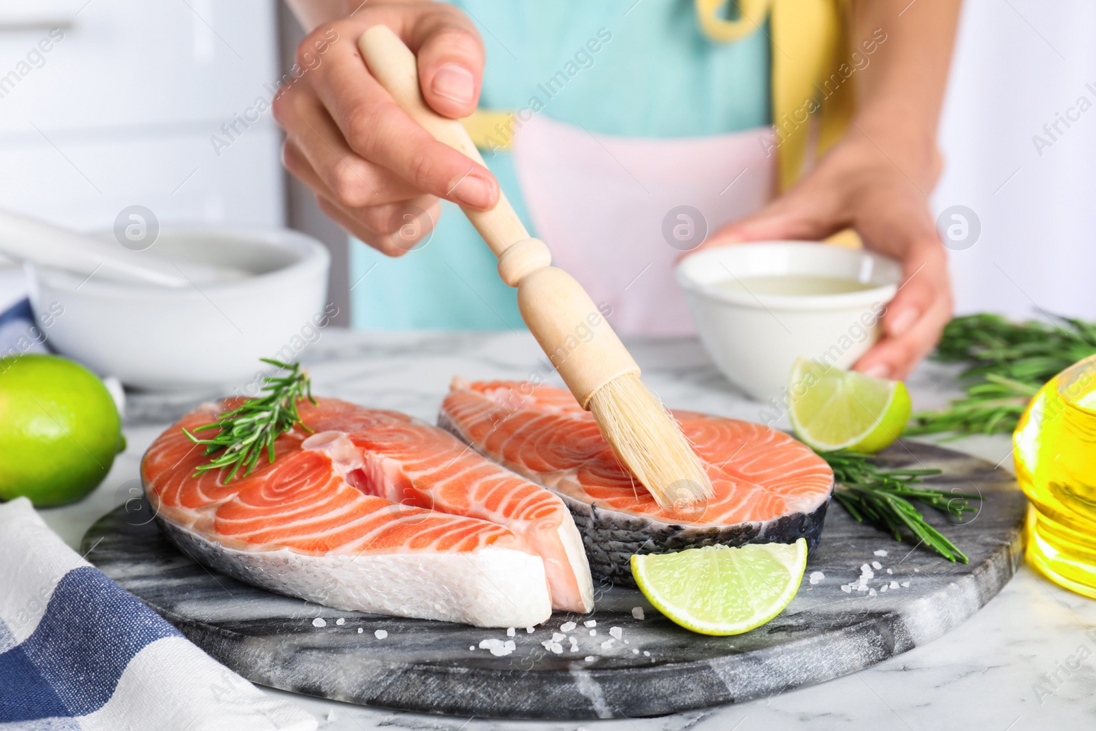 Photo of Woman marinating fresh raw salmon at table, closeup. Fish delicacy