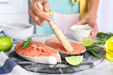 Woman marinating fresh raw salmon at table, closeup. Fish delicacy