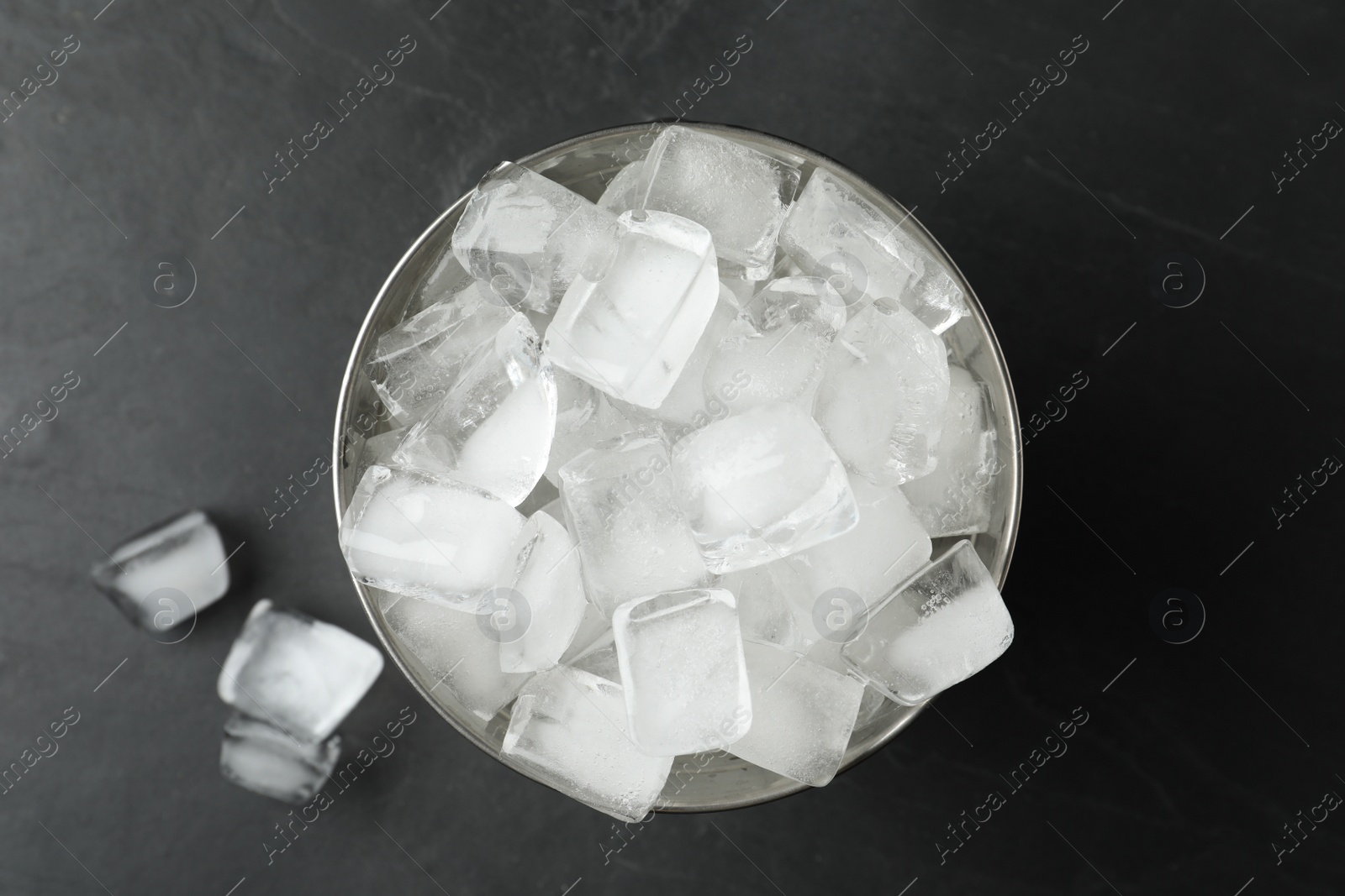 Photo of Metal bucket with ice cubes on grey background, flat lay