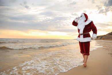 Photo of Santa Claus on beach, space for text. Christmas vacation