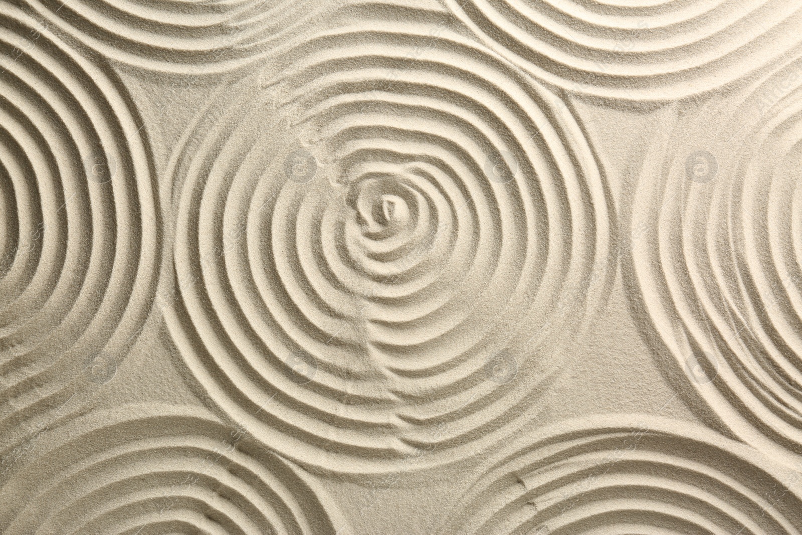 Photo of Beautiful spirals on sand, top view. Zen garden