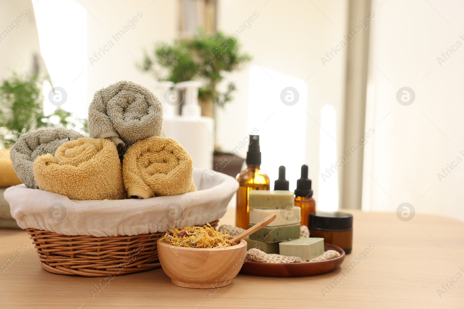 Photo of Dry flowers, soap bars, bottles of essential oils, jar with cream and towels on wooden table indoors, space for text. Spa time