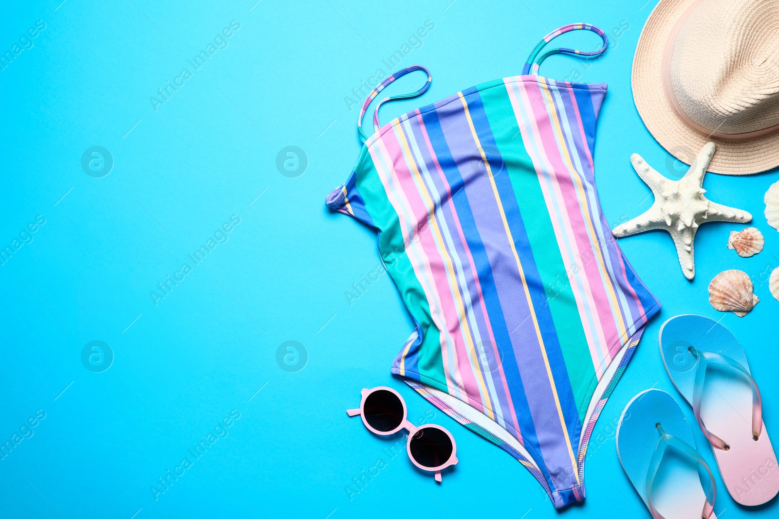 Photo of Flat lay composition with one-piece swimsuit and beach objects on color background