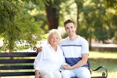 Man with elderly mother on bench in park