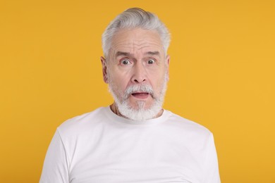 Photo of Portrait of surprised senior man on yellow background