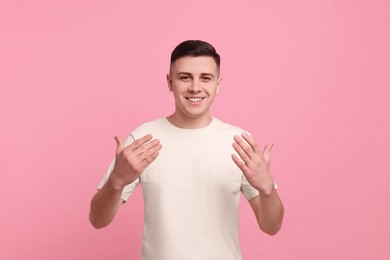 Photo of Handsome man inviting to come in against pink background