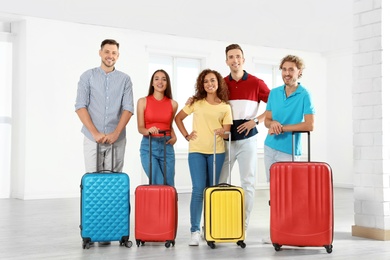 Group of young people with suitcases in light room