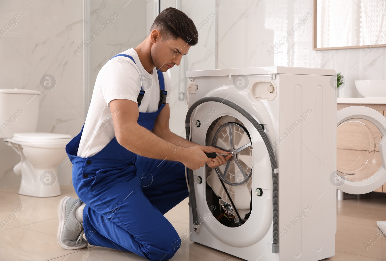 Photo of Professional plumber repairing washing machine in bathroom