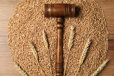 Photo of Judge's gavel, wheat ears and grains on wooden table, top view. Agricultural deal