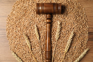 Judge's gavel, wheat ears and grains on wooden table, top view. Agricultural deal