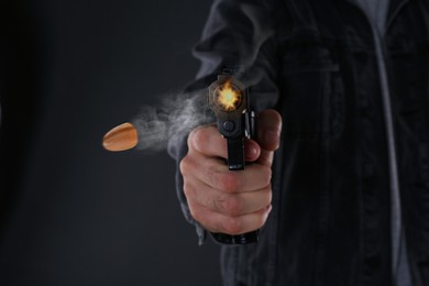 Image of Man shooting from gun on black background, closeup