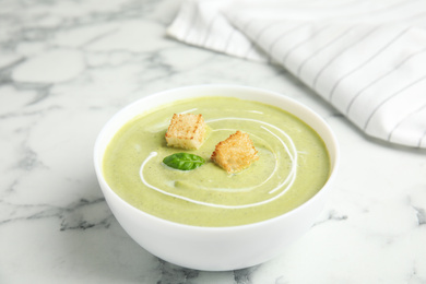 Delicious broccoli cream soup with croutons served on white marble table