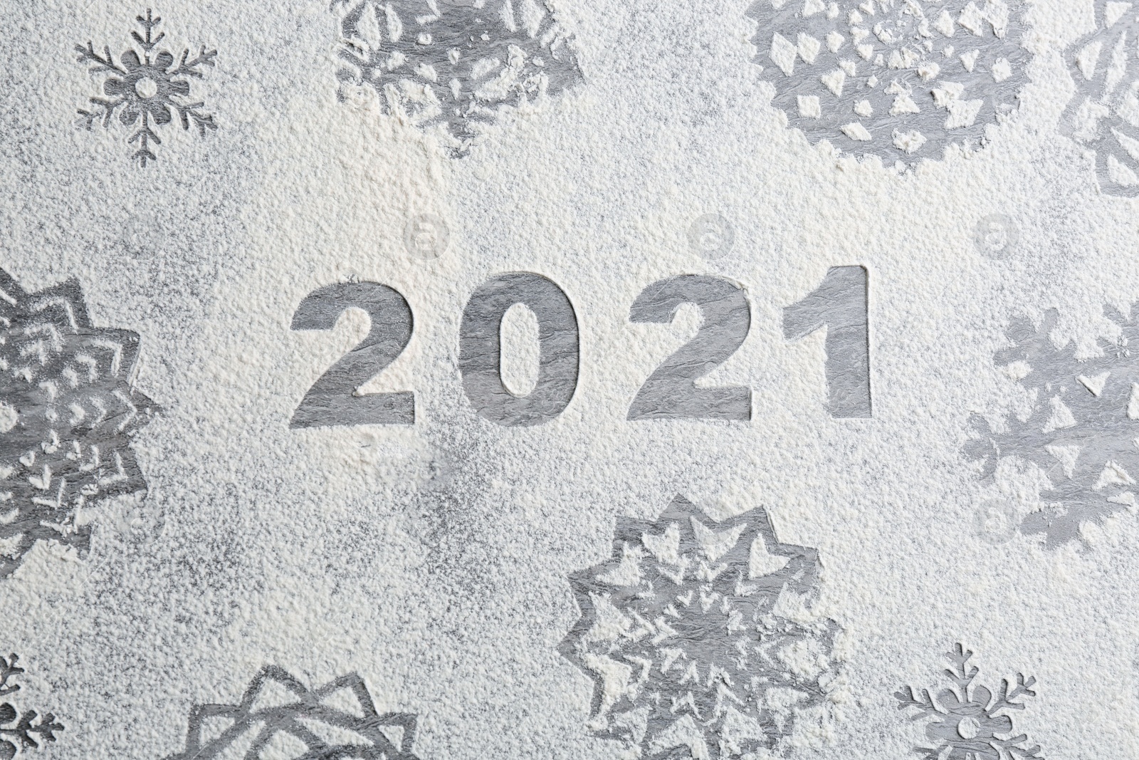 Photo of Snowflakes and number 2021 made of flour on grey table, top view