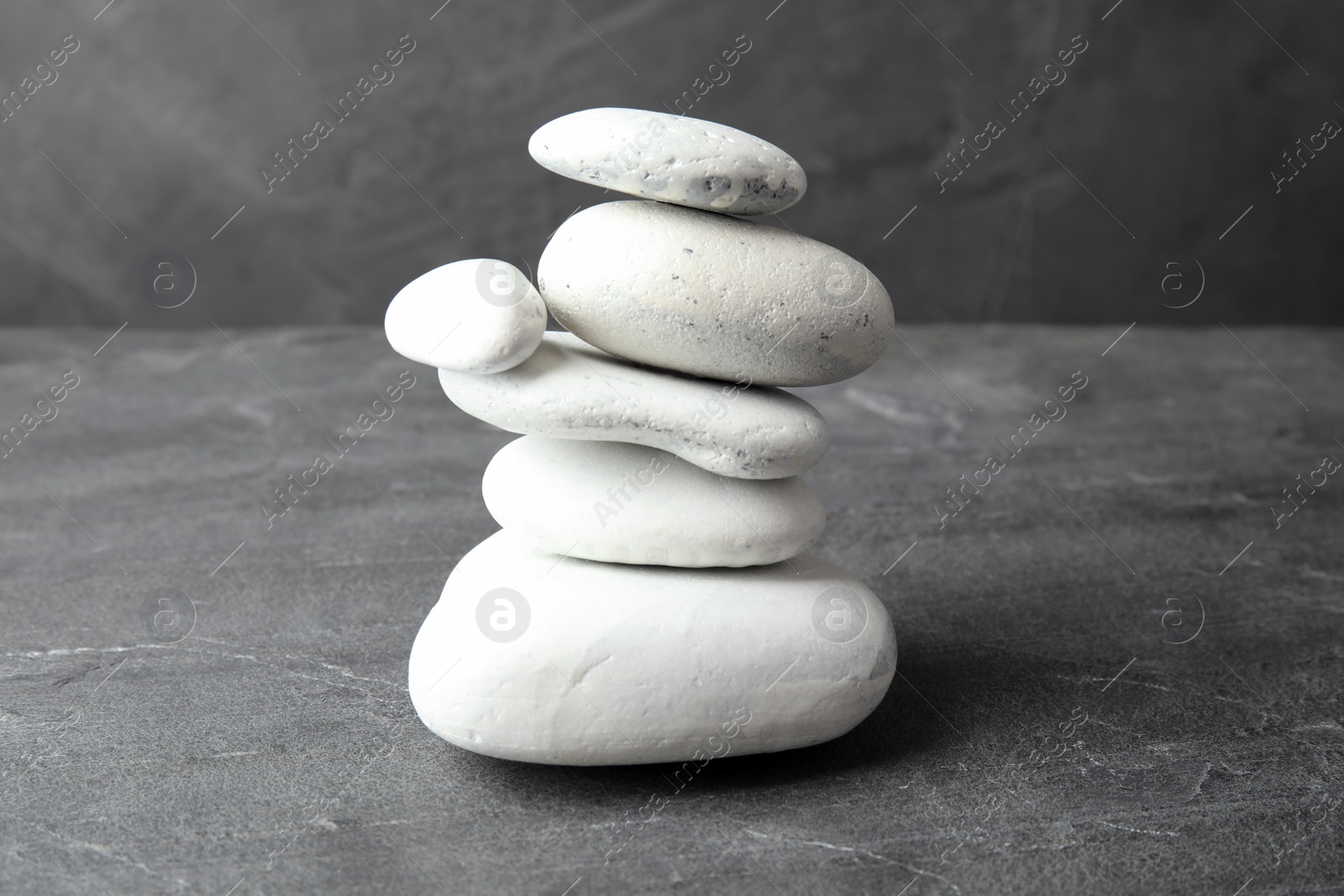 Photo of Stack of zen stones on table against grey background