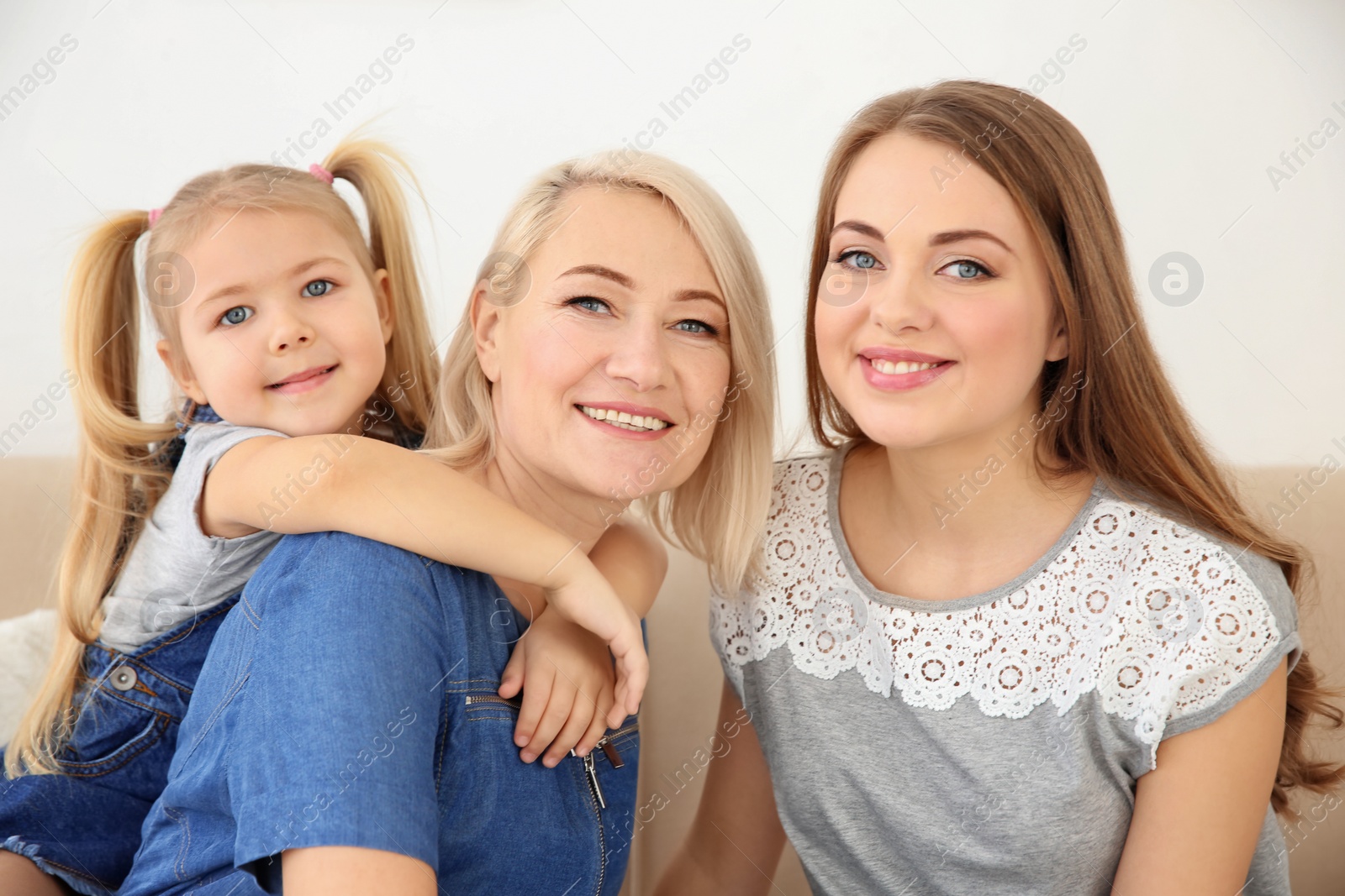 Photo of Happy young woman with her mother and daughter at home