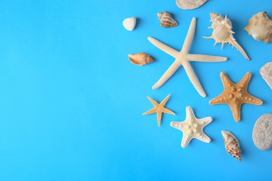 Many starfishes, stones and shells on blue background, flat lay. Space for text