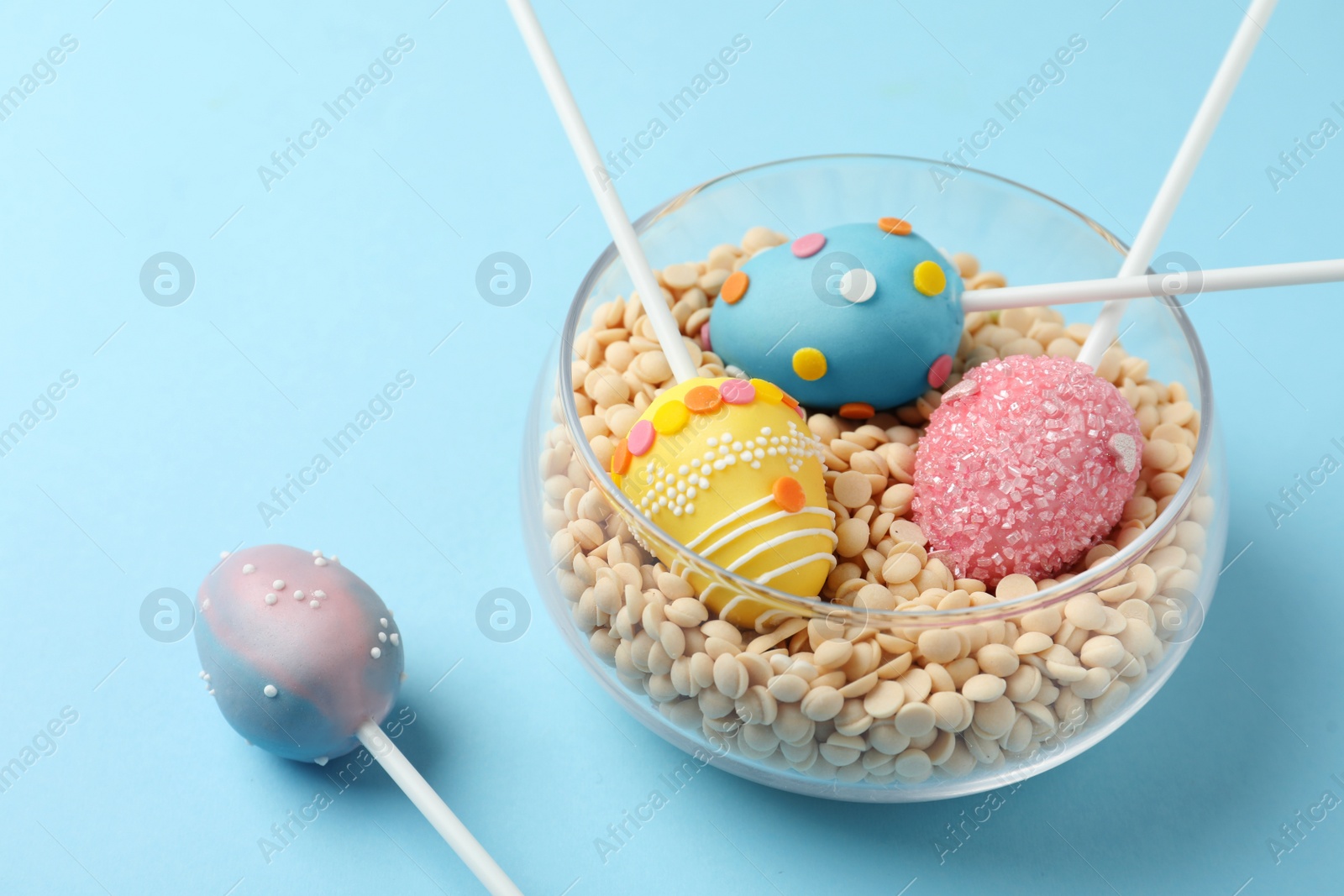 Photo of Egg shaped cake pops for Easter celebration on light blue background