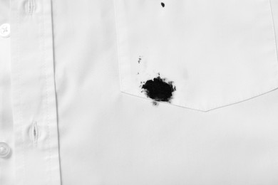 Photo of Stain of black ink on white shirt, top view