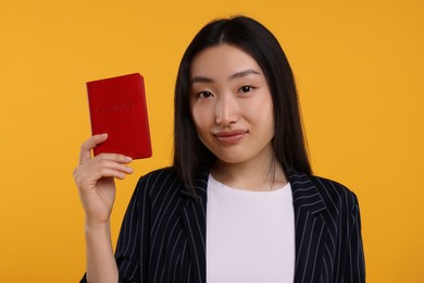 Photo of Immigration. Woman with passport on orange background