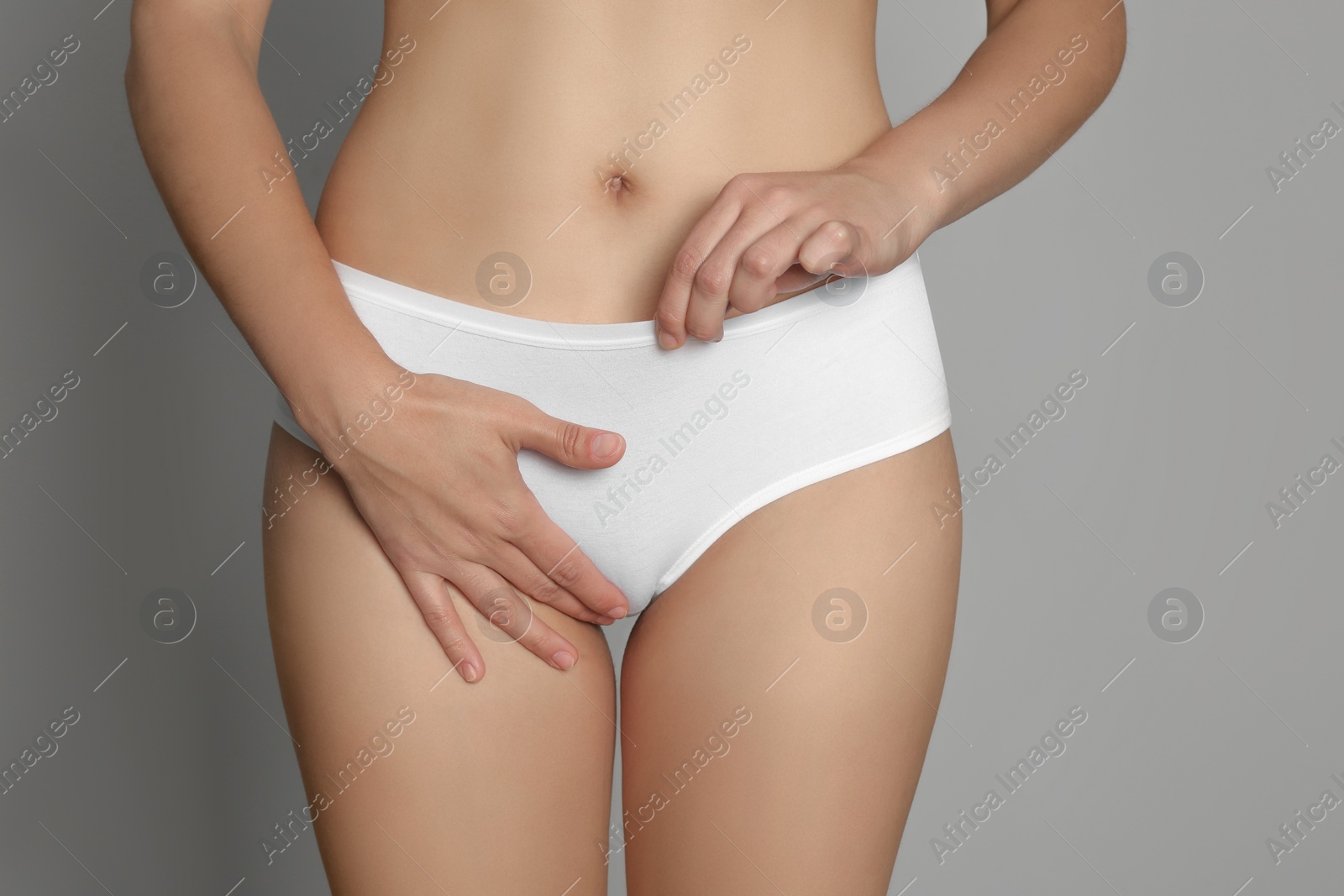 Photo of Woman suffering from genital herpes on light grey background, closeup