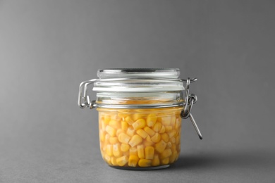 Photo of Jar of pickled sweet corn on grey background