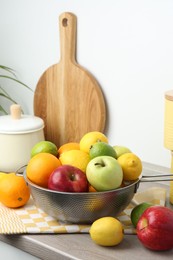 Photo of Metal colander with different fruits on countertop in kitchen