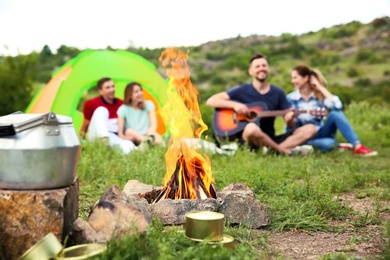 Photo of Group of people resting outdoors, focus on bonfire. Camping season