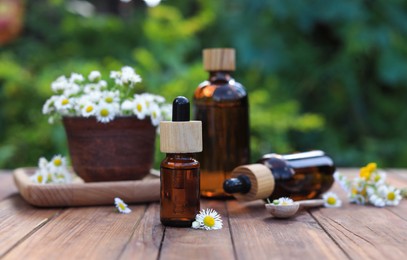Photo of Bottles of essential oil and flowers on wooden table