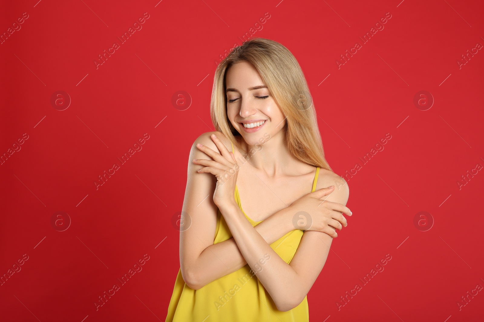 Photo of Portrait of beautiful young woman with blonde hair on red background