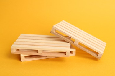 Photo of Three small wooden pallets on orange background