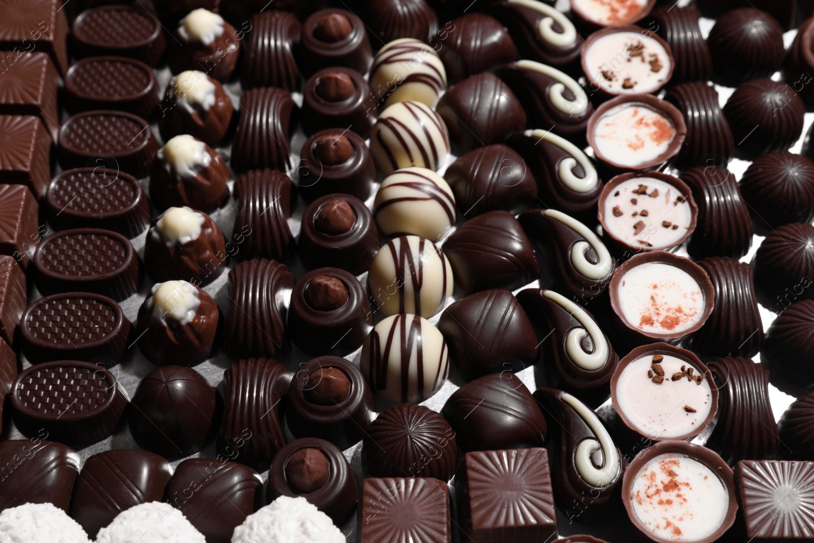 Photo of Many different delicious chocolate candies as background, closeup view