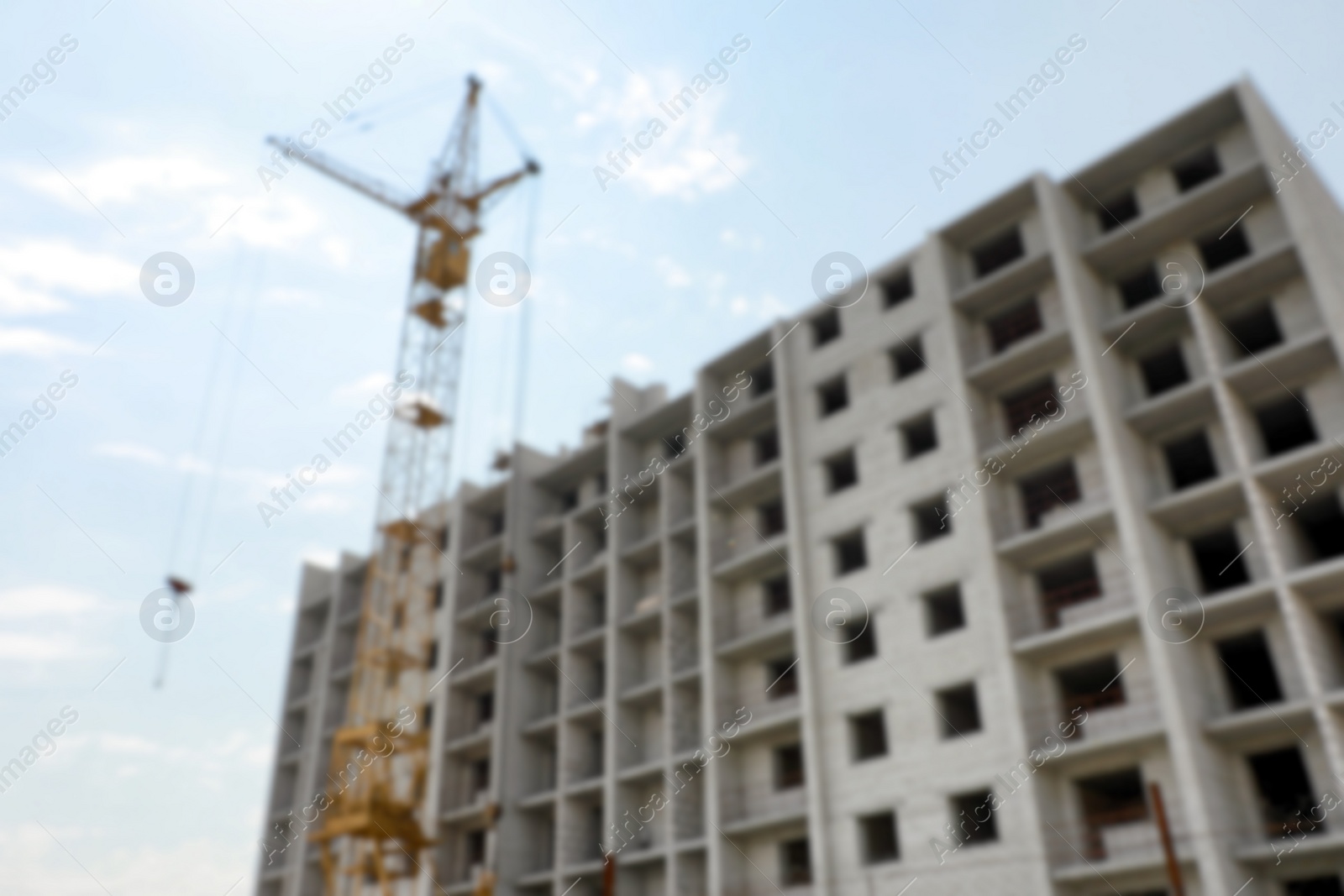 Photo of Blurred view of unfinished building and construction crane outdoors