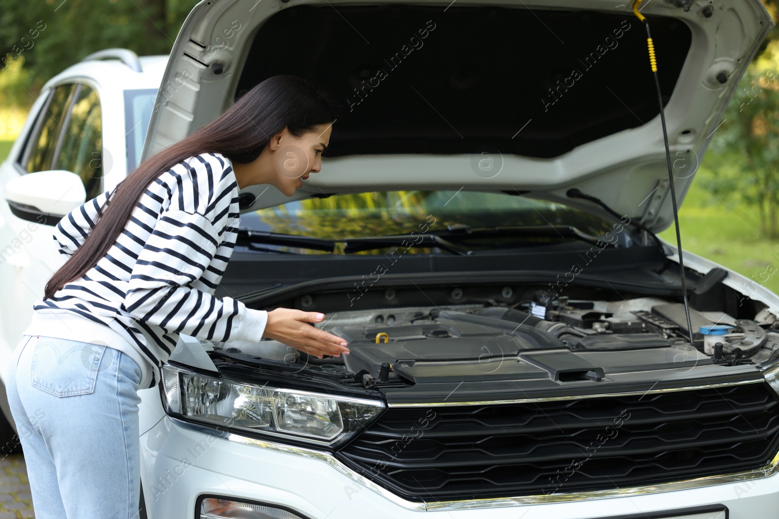 Photo of Stressed young woman near broken car outdoors