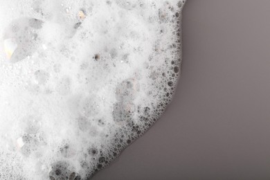 Photo of White foam with bubbles on grey background, top view. Space for text