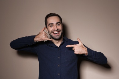 Photo of Man showing CALL ME gesture in sign language on color background