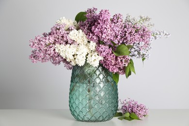 Photo of Beautiful lilac flowers in glass vase on light background