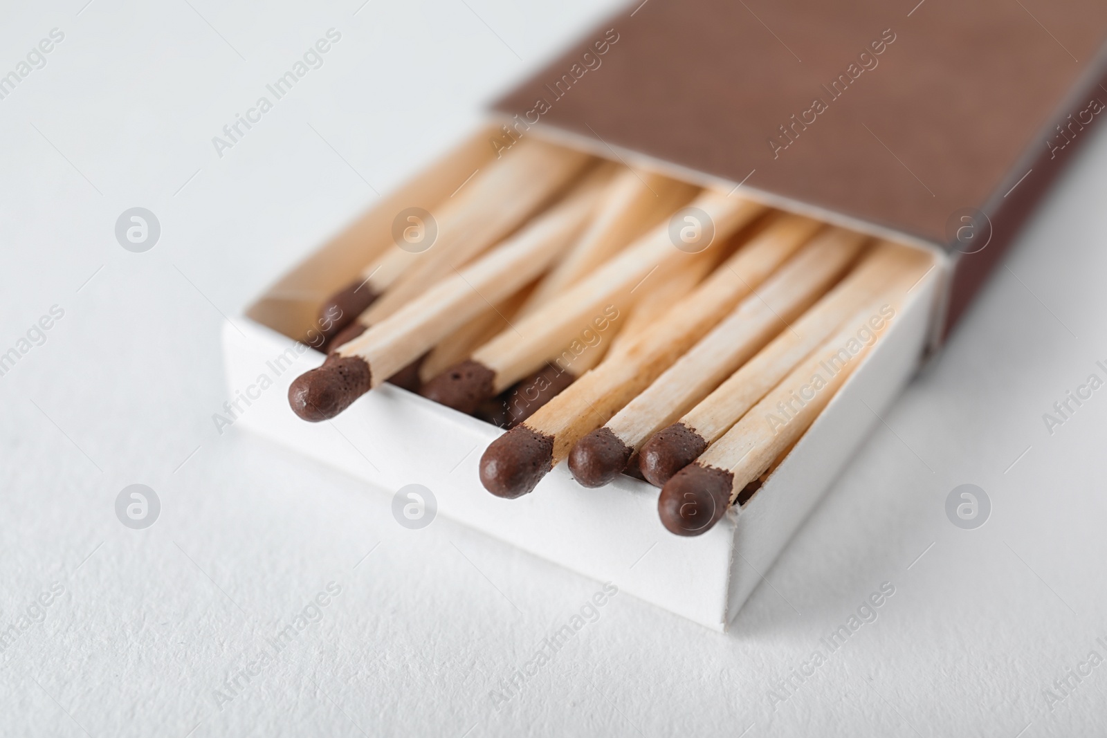 Photo of Cardboard box with matches on light background, closeup