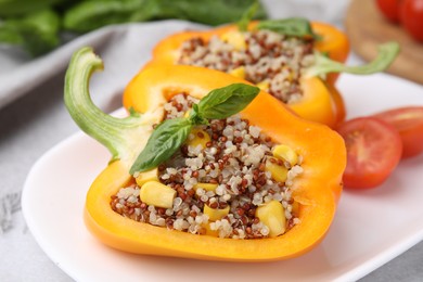 Photo of Quinoa stuffed bell pepper with basil on light table, closeup