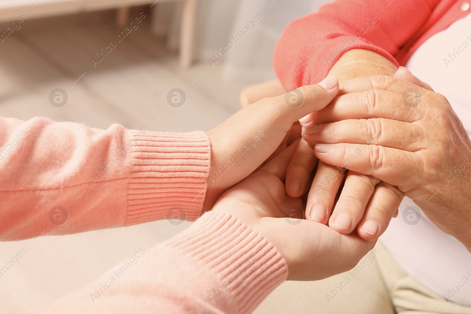 Photo of Helping hands on blurred background, closeup. Elderly care concept