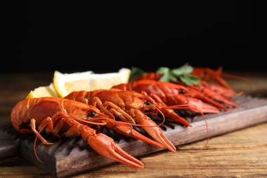 Delicious boiled crayfishes on wooden table, closeup