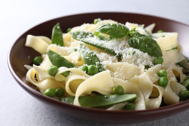 Delicious pasta with green peas and cheese on grey table, closeup