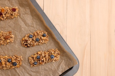 Photo of Baking tray with different granola bars on wooden table, flat lay and space for text. Healthy snack