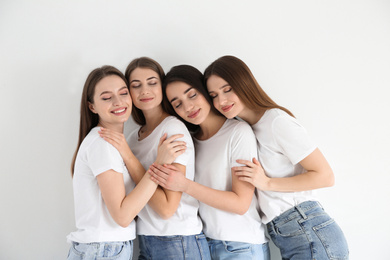 Photo of Beautiful young ladies in jeans and white t-shirts on light background. Woman's Day